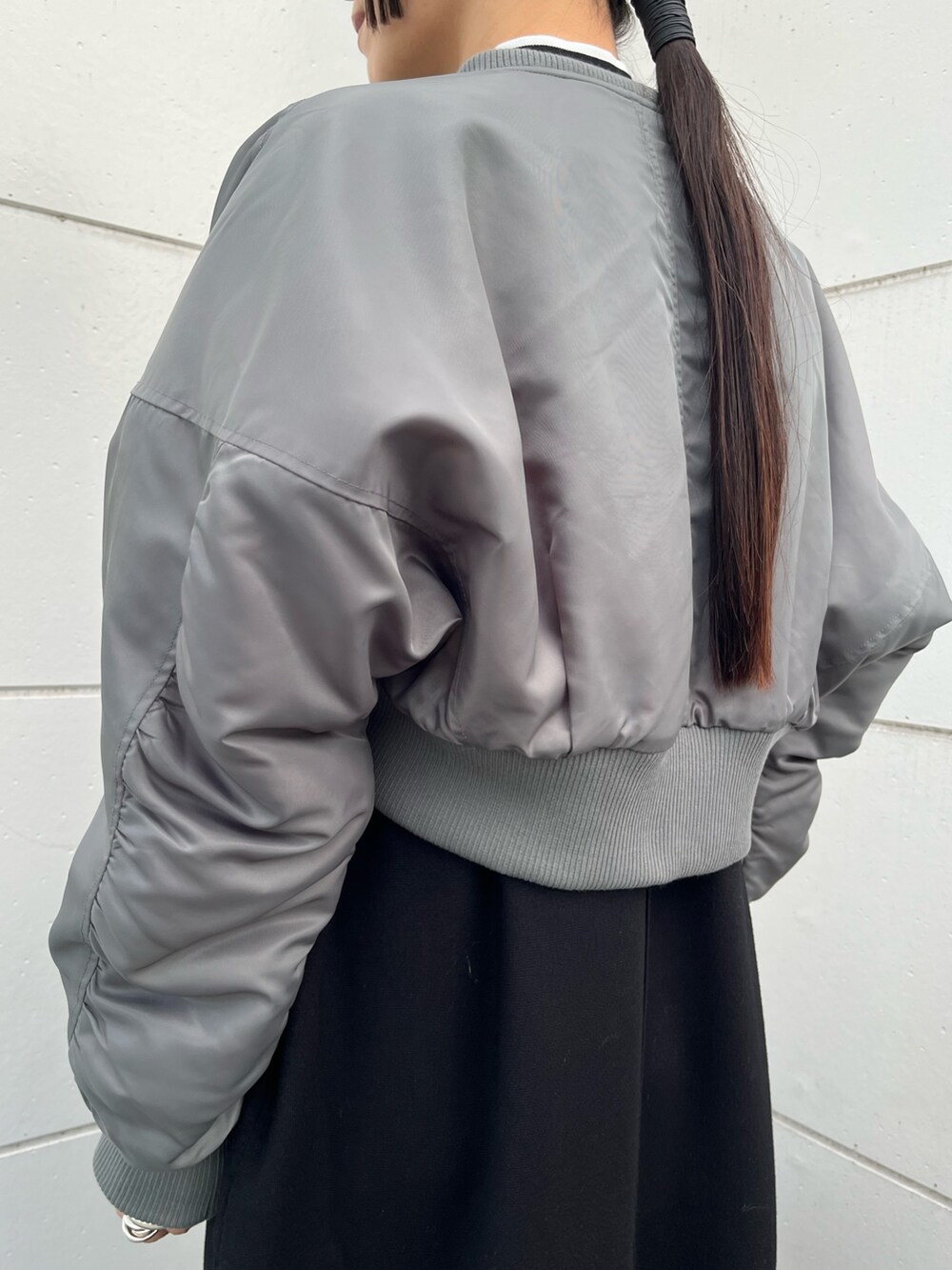 ブラック系のワンピース、グレー系のMA-1、シルバー系のハンドバッグを着用したレディースの冬コーディネートの6枚目の写真