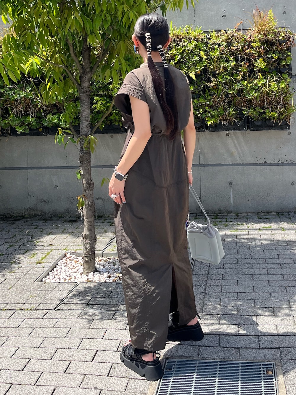 グリーン系のワンピース、ブラック系のサンダル、グレー系のショルダーバッグを着用したレディースの夏コーディネートの3枚目の写真