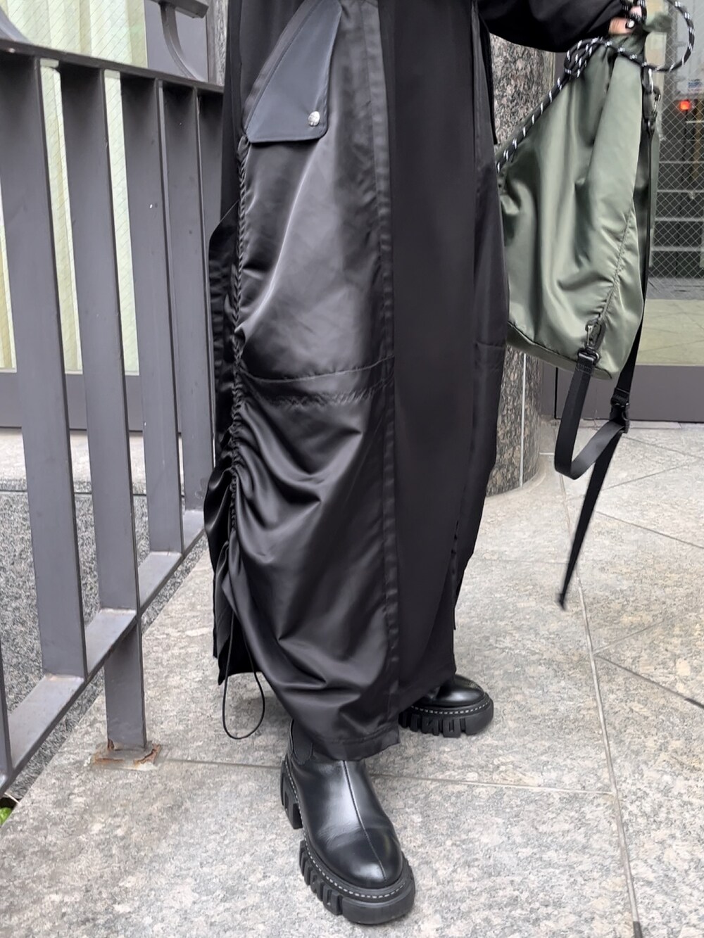 ブラック系のブーツ、ブラック系のワンピース、グリーン系のショルダーバッグを着用したレディースの秋コーディネートの4枚目の写真