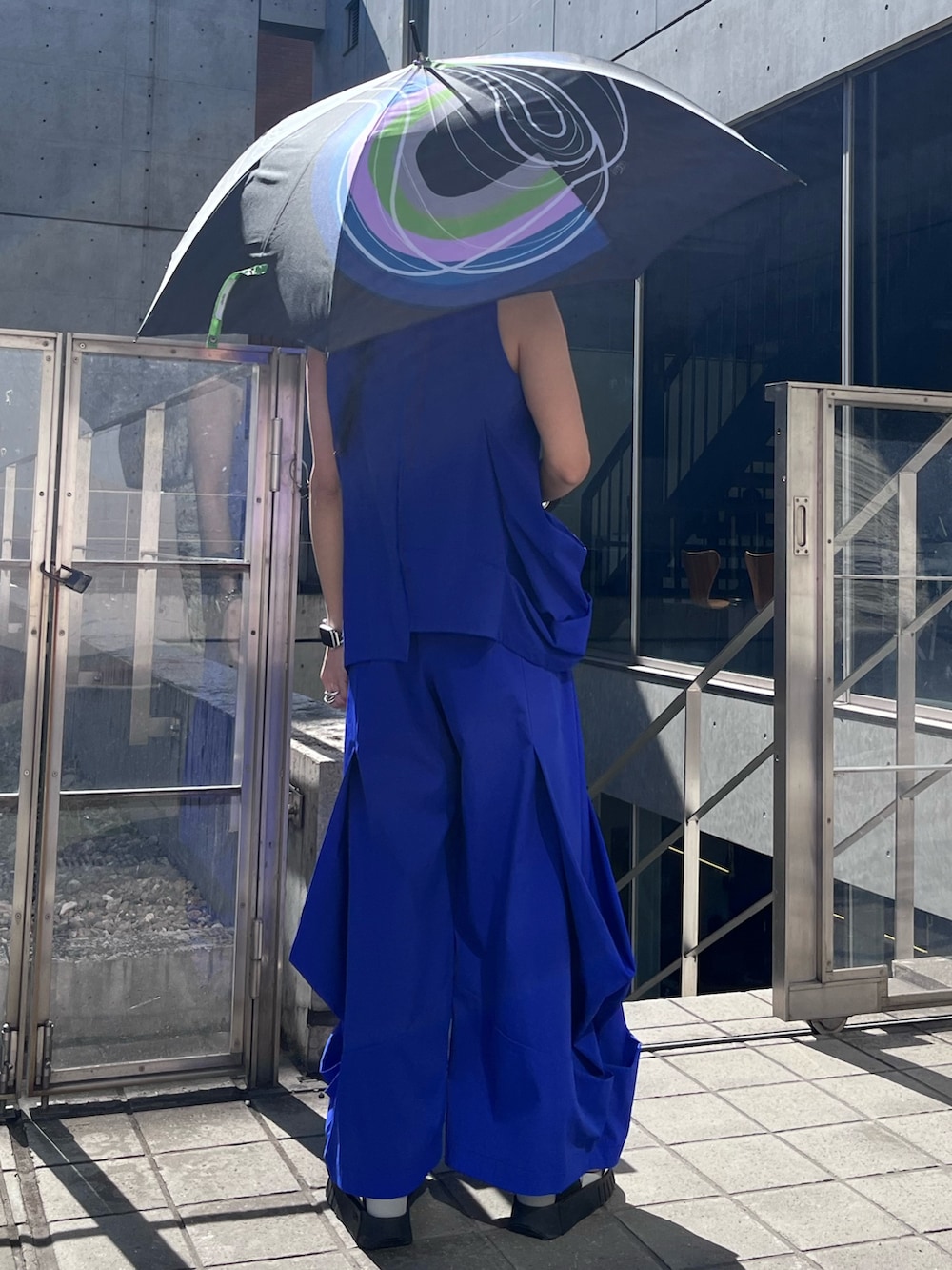 ブルー系のタンクトップ、ブルー系のその他パンツ、ブラック系の長傘を着用したレディースの春コーディネートの2枚目の写真