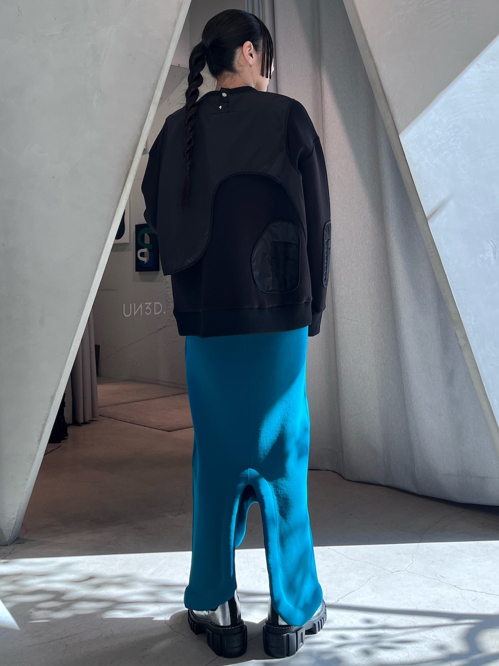 ブラック系のスウェット、ブルー系のスカート、ブラック系のブーツを着用したレディースの冬コーディネートの2枚目の写真