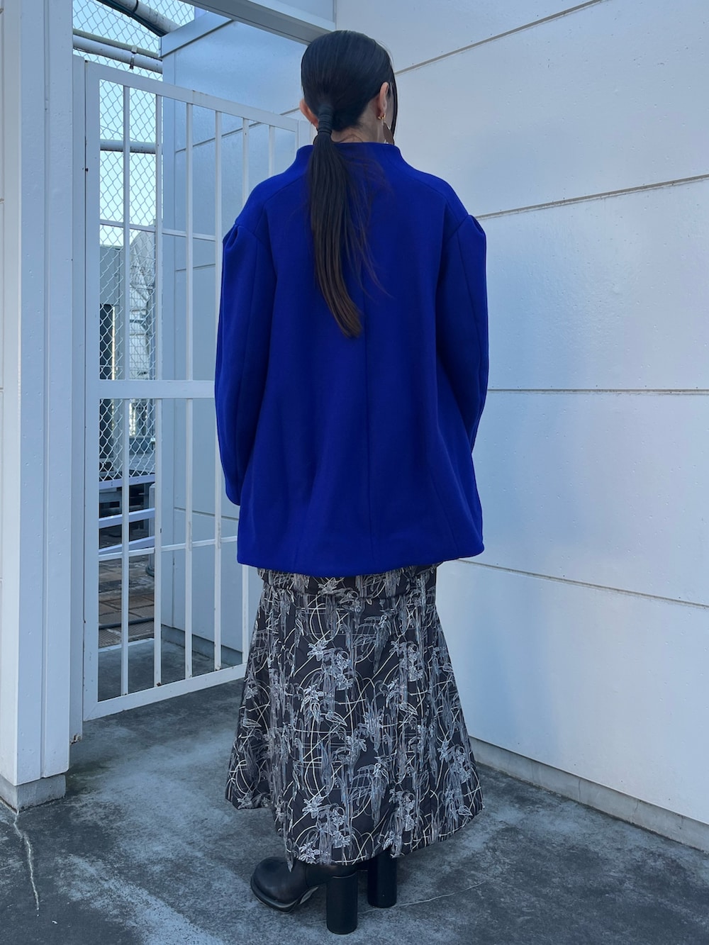 ブルー系のその他アウター、ブラック系のスカート、ブラック系のブーツを着用したレディースの冬コーディネートの2枚目の写真