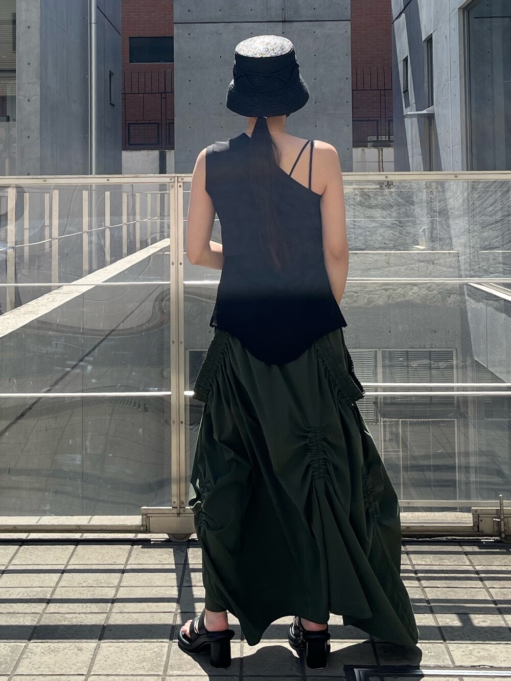 ブラック系のTシャツ/カットソー、グリーン系のスカート、ブラック系のサンダルを着用したレディースの春コーディネートの2枚目の写真