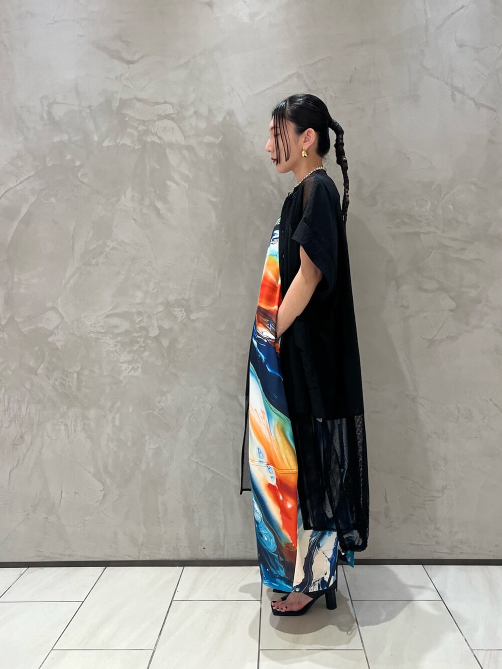 オレンジ系のワンピース、ブラック系のシャツ/ブラウス、ブラック系のサンダルを着用したレディースの春コーディネートの3枚目の写真