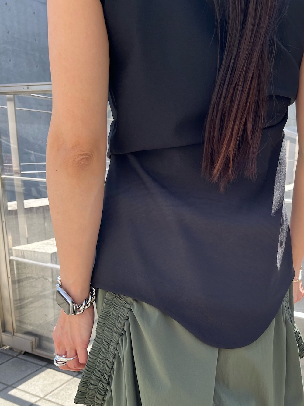 ブラック系のTシャツ/カットソー、グリーン系のスカート、ブラック系のサンダルを着用したレディースの春コーディネートの6枚目の写真