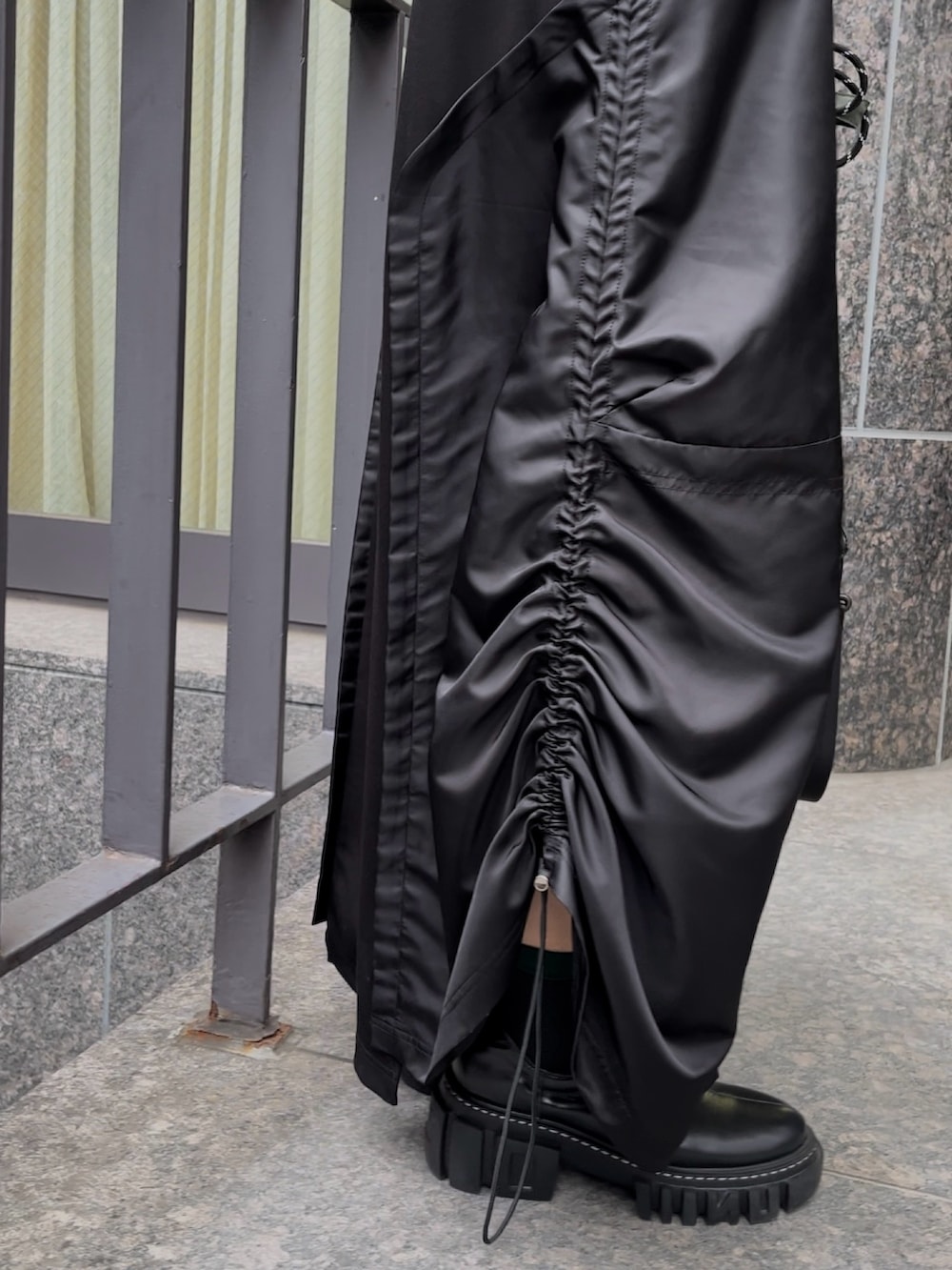 ブラック系のブーツ、ブラック系のワンピース、グリーン系のショルダーバッグを着用したレディースの秋コーディネートの5枚目の写真