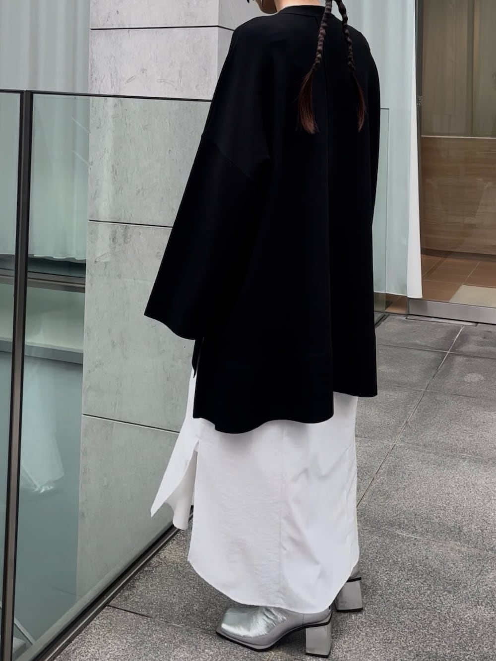 ブラック系のニット/セーター、ホワイト系のワンピース、シルバー系のブーツを着用したレディースの冬コーディネートの3枚目の写真