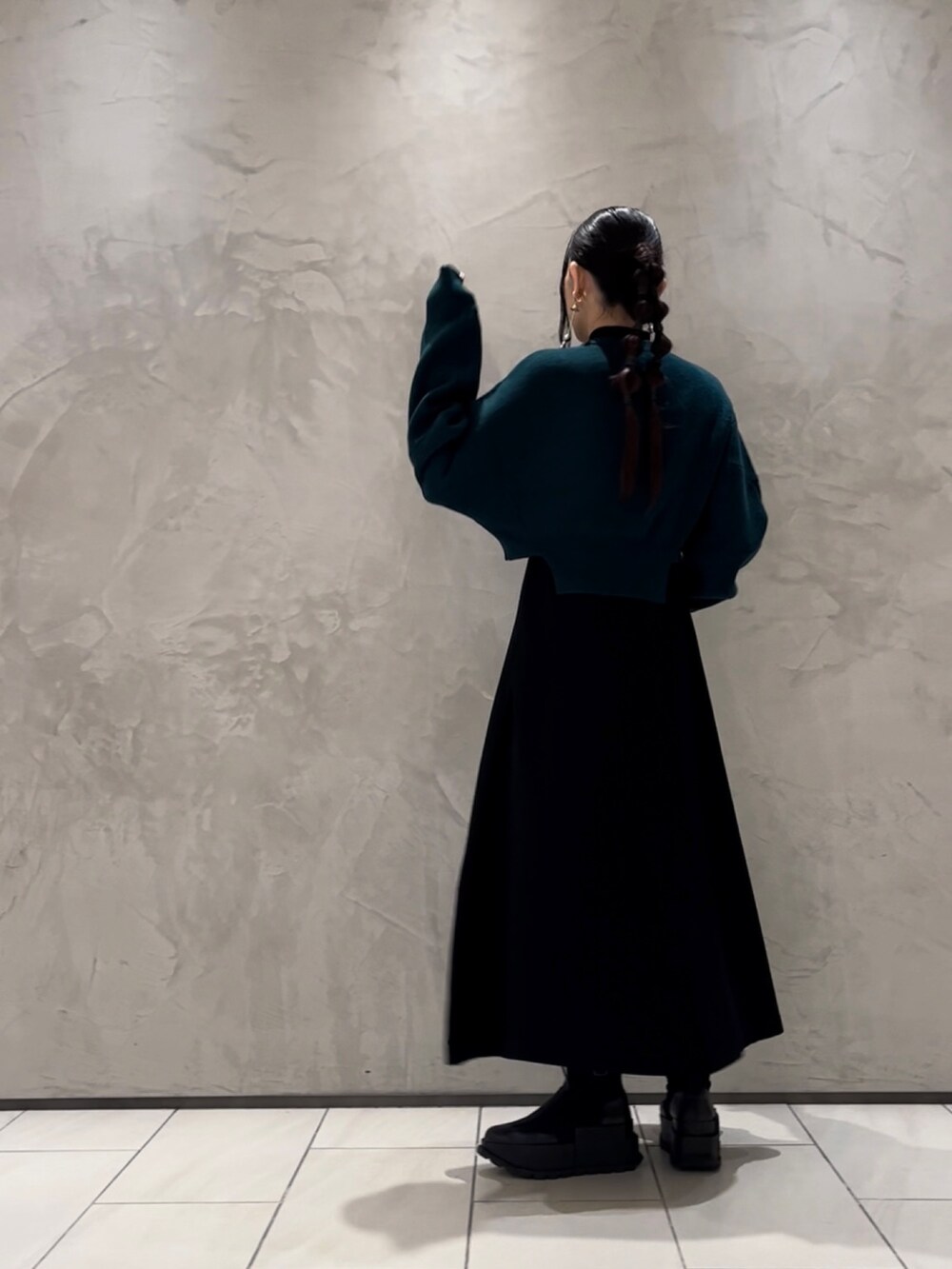 グリーン系のニット/セーター、ブラック系のワンピース、ブラック系のブーツを着用したレディースの秋コーディネートの3枚目の写真