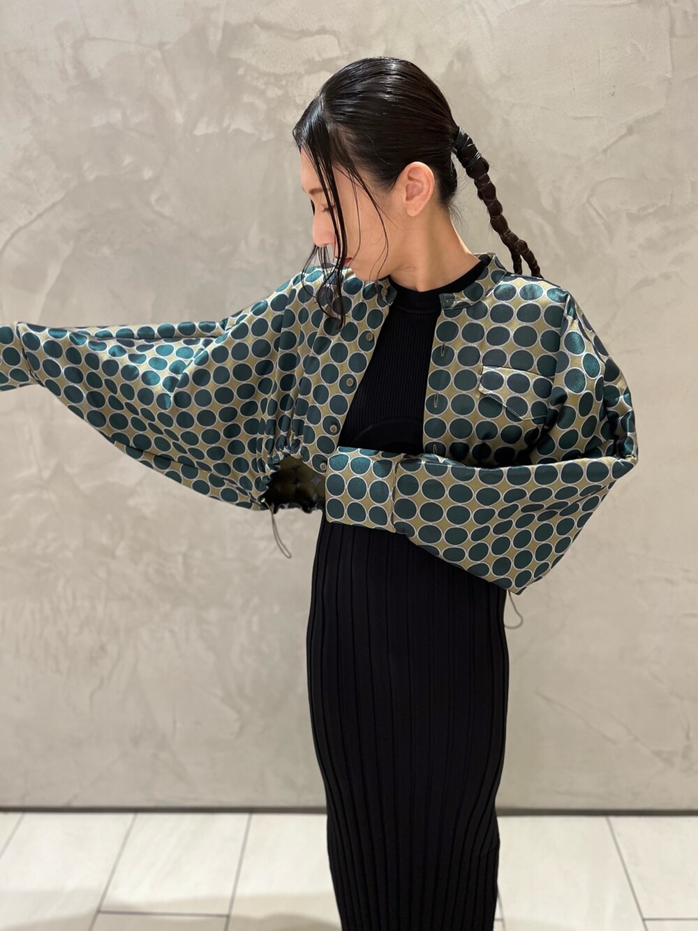 グリーン系のブルゾン、ブラック系のワンピース、ベージュ系のブーツを着用したレディースの冬コーディネートの4枚目の写真