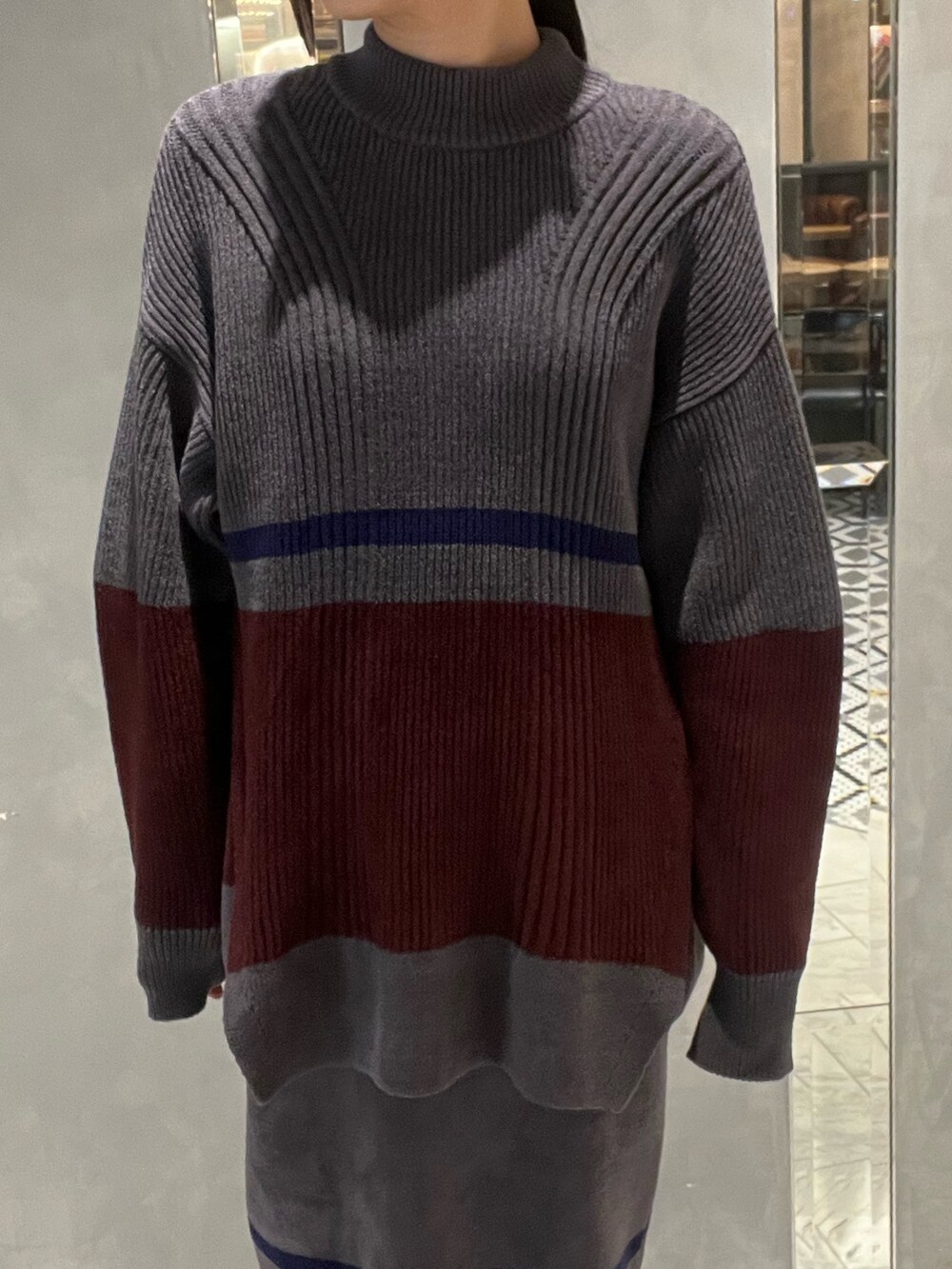 シルバー系のスニーカー、シルバー系のショルダーバッグ、グレー系のニット/セーターを着用したレディースの冬コーディネートの3枚目の写真