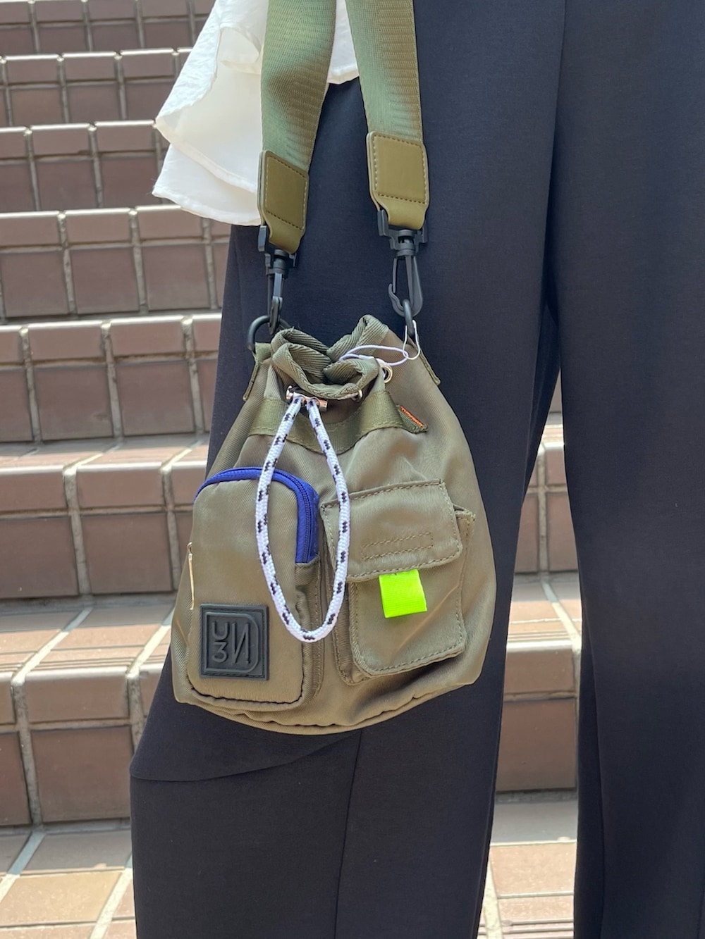 ブラック系のニット/セーター、ホワイト系のシャツ/ブラウス、グリーン系のショルダーバッグを着用したレディースの秋コーディネートの5枚目の写真