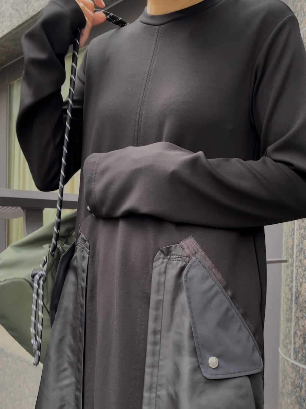 ブラック系のブーツ、ブラック系のワンピース、グリーン系のショルダーバッグを着用したレディースの秋コーディネートの3枚目の写真