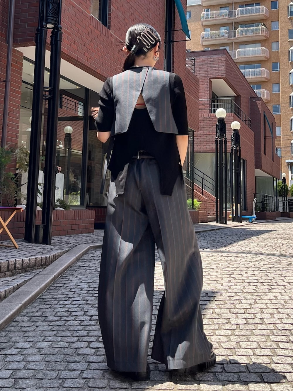 グレー系のスラックス、ブラック系のパンプス、ブラック系のニット/セーターを着用したレディースの春コーディネートの2枚目の写真