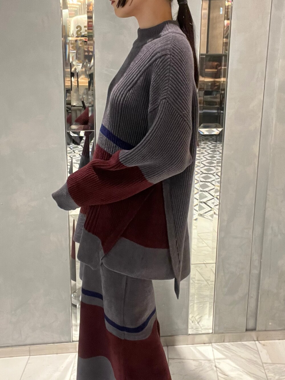 シルバー系のスニーカー、シルバー系のショルダーバッグ、グレー系のニット/セーターを着用したレディースの冬コーディネートの4枚目の写真