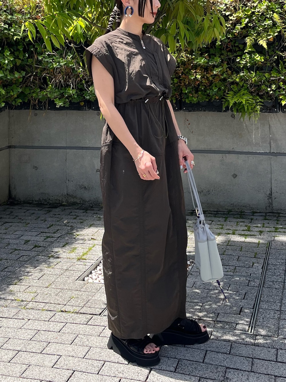 グリーン系のワンピース、ブラック系のサンダル、グレー系のショルダーバッグを着用したレディースの夏コーディネートの2枚目の写真