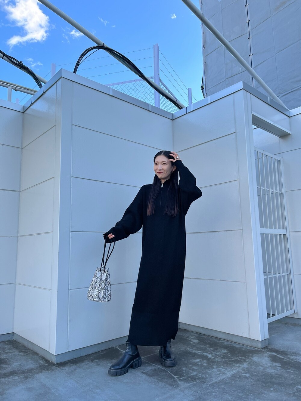 ブラック系のワンピース、その他のショルダーバッグ、ブラック系のブーツを着用したレディースの冬コーディネートの2枚目の写真