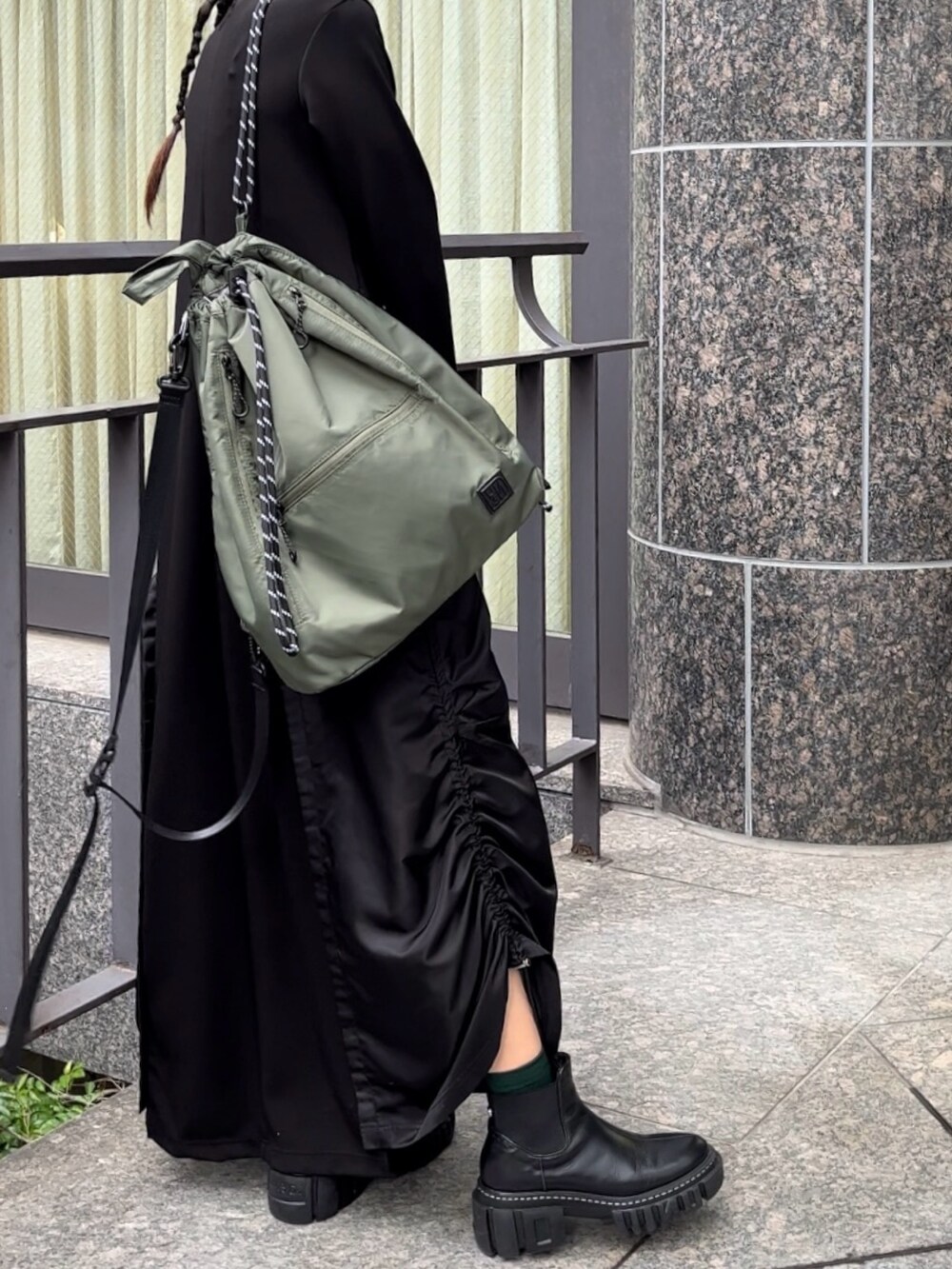 ブラック系のブーツ、ブラック系のワンピース、グリーン系のショルダーバッグを着用したレディースの秋コーディネートの6枚目の写真