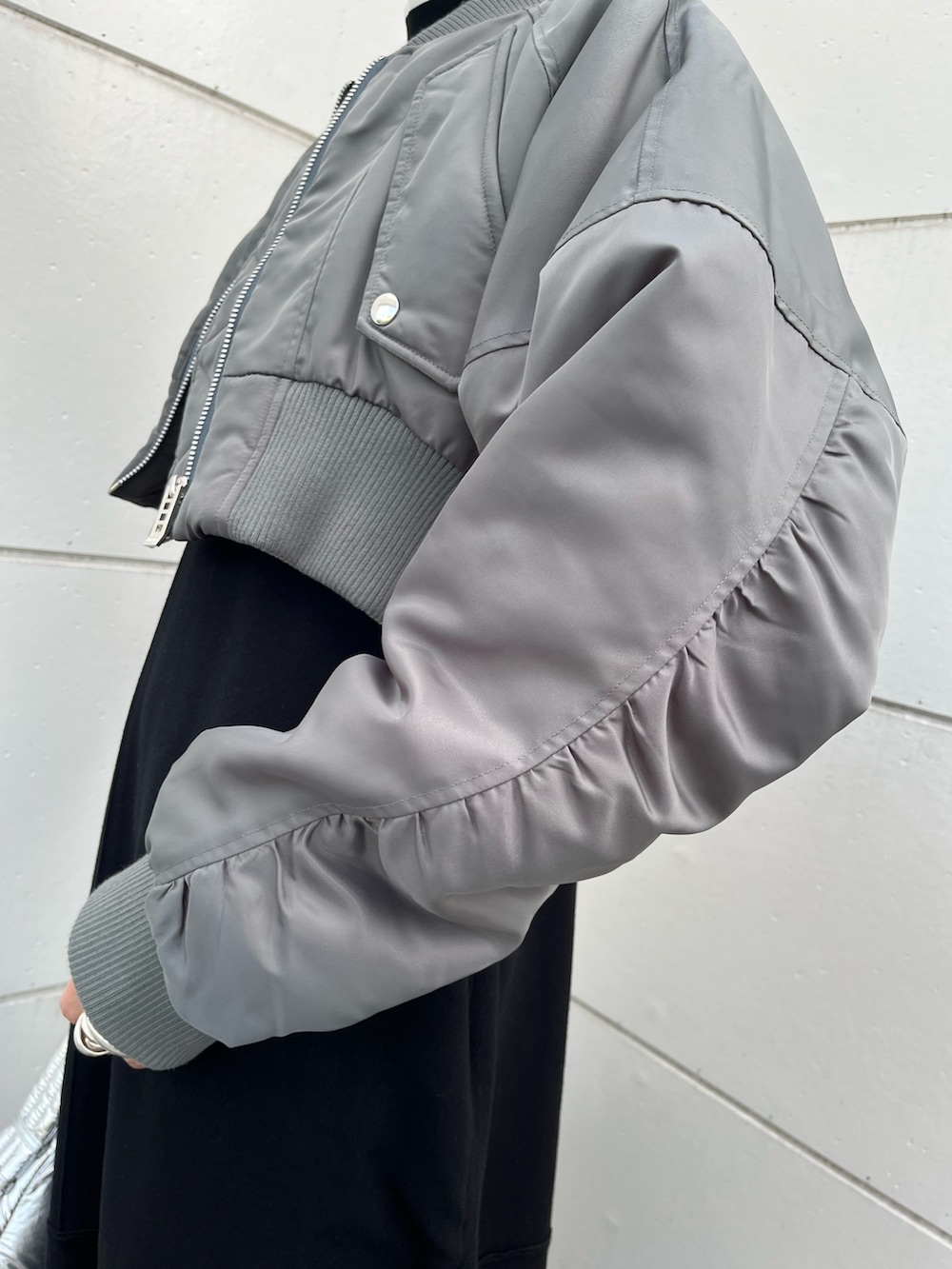 ブラック系のワンピース、グレー系のMA-1、シルバー系のハンドバッグを着用したレディースの冬コーディネートの7枚目の写真