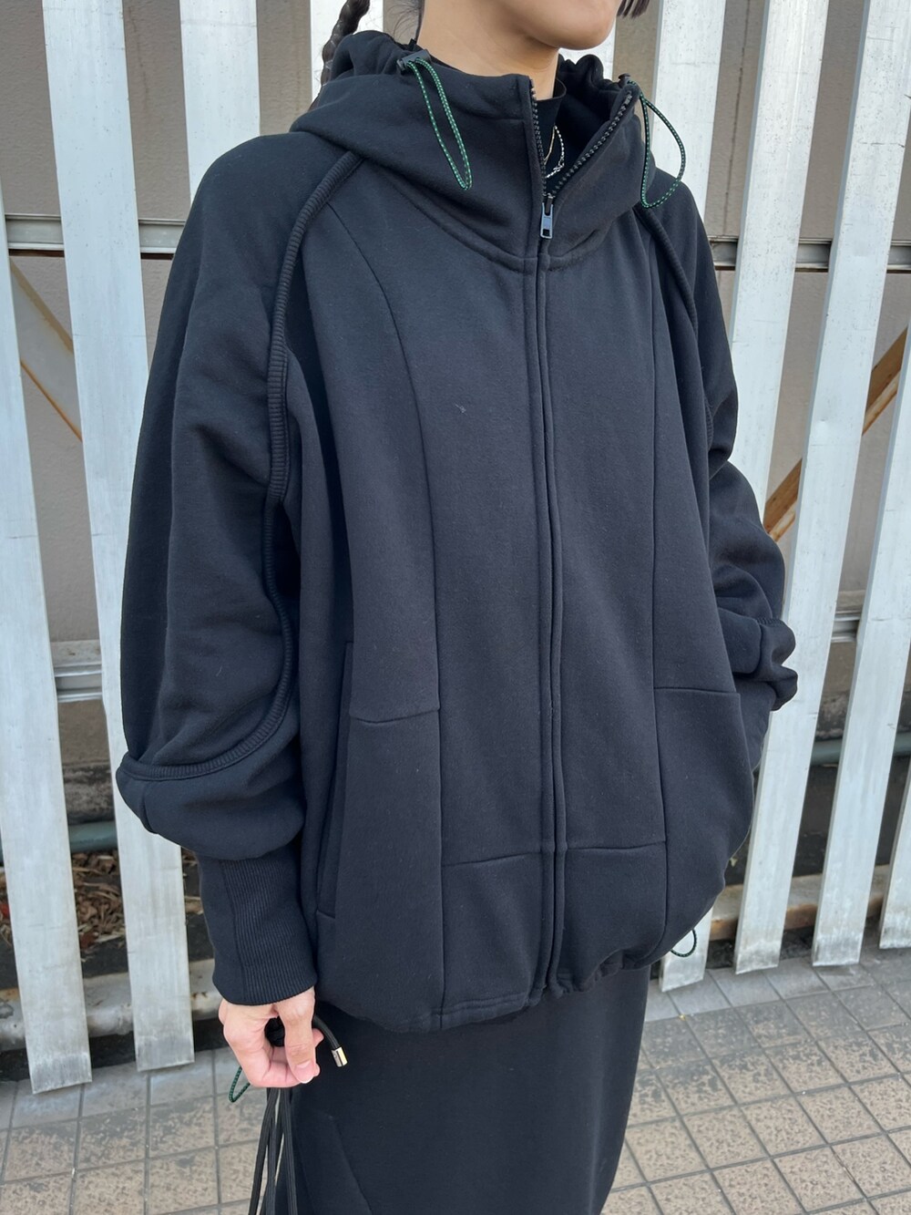 ブラック系のパーカー、ブラック系のスカート、ブラック系のブーツを着用したレディースの冬コーディネートの4枚目の写真