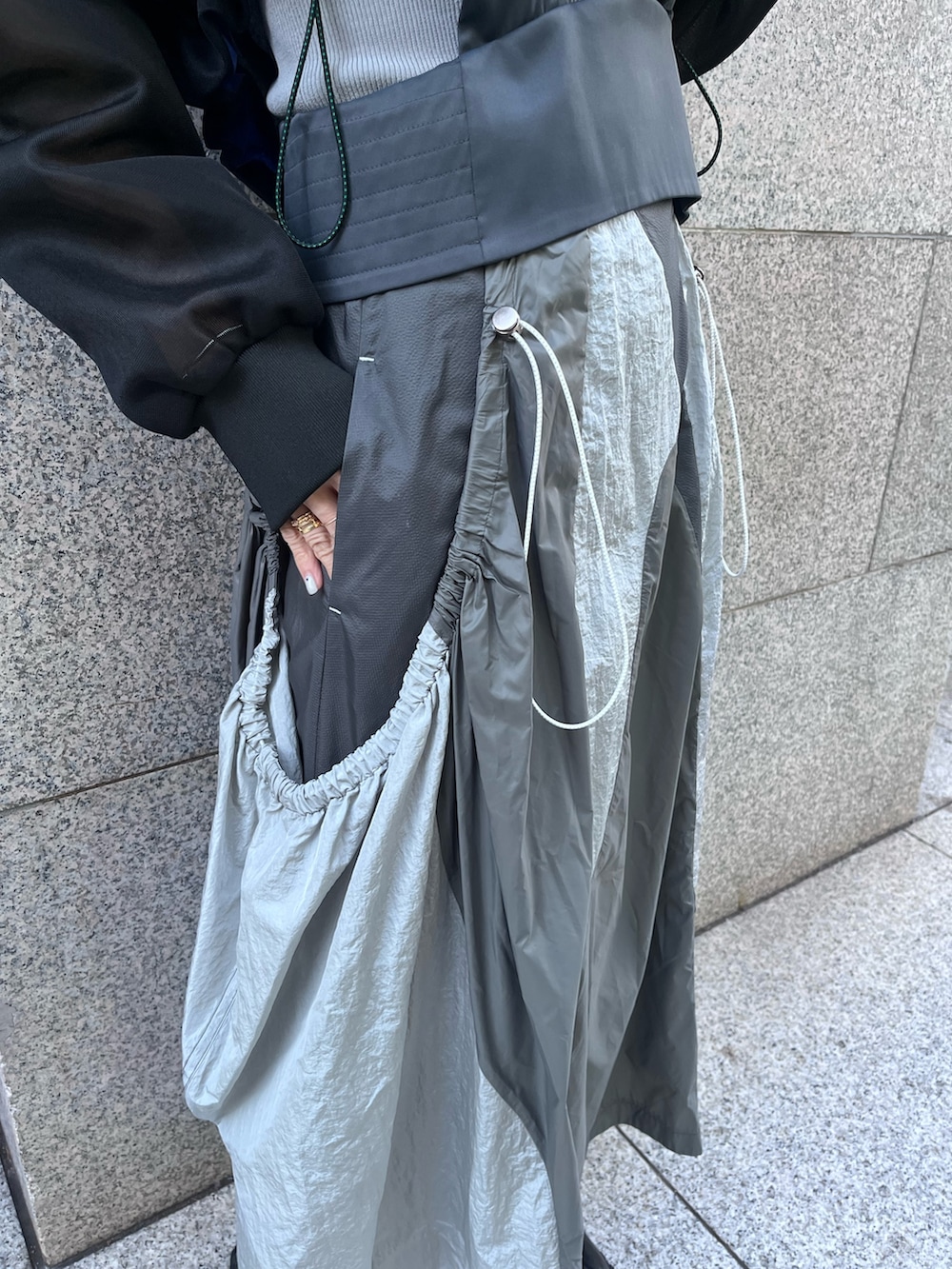 ブラック系のブルゾン、グレー系のタンクトップ、グレー系のジャンパースカートを着用したレディースの春コーディネートの7枚目の写真