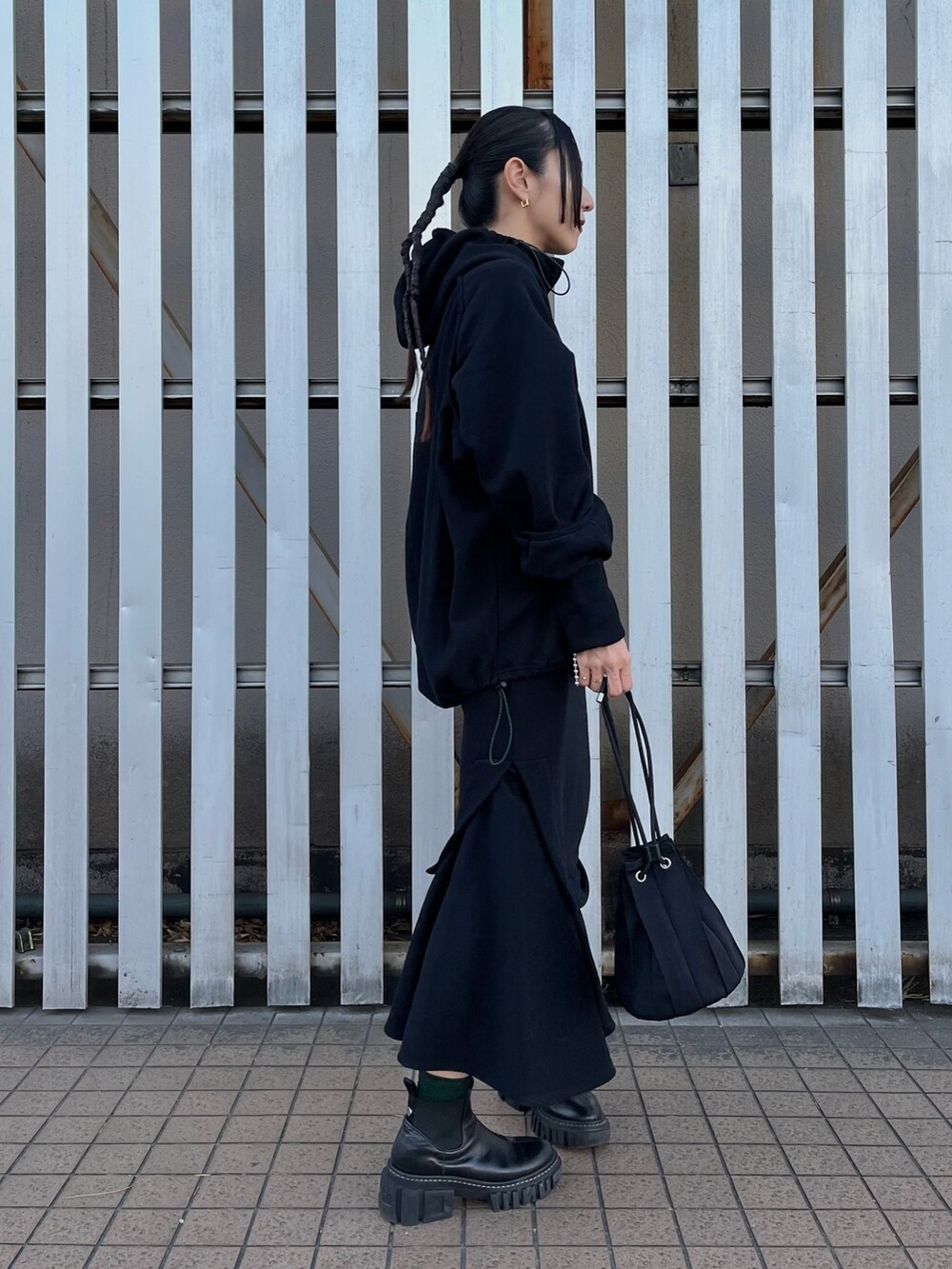 ブラック系のパーカー、ブラック系のスカート、ブラック系のブーツを着用したレディースの冬コーディネートの2枚目の写真