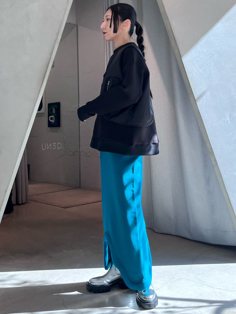 ブラック系のスウェット、ブルー系のスカート、ブラック系のブーツを着用したレディースの冬コーディネートの3枚目の写真