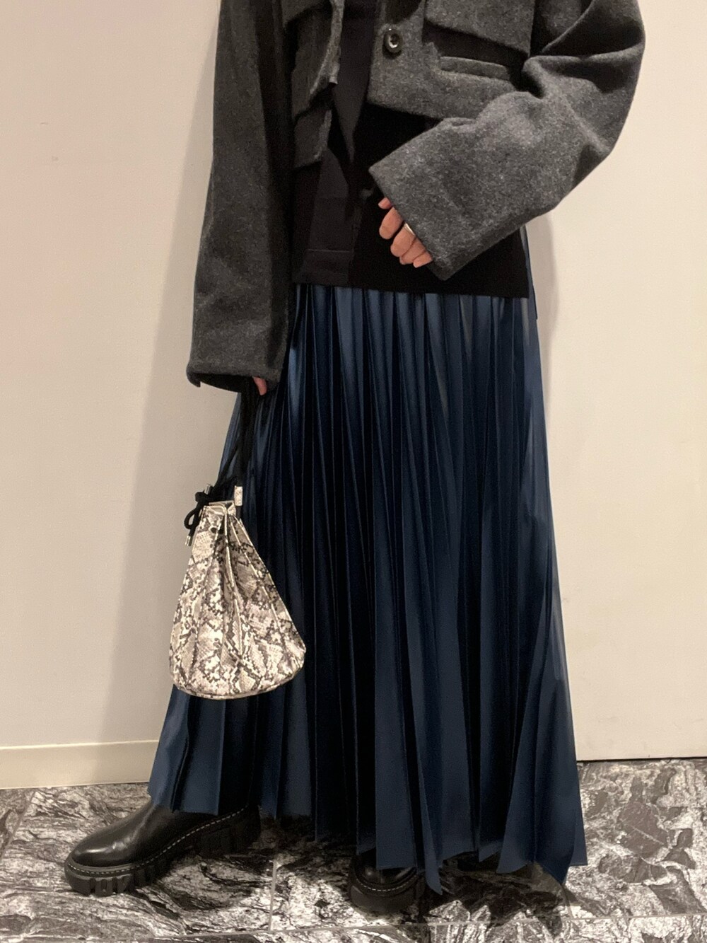 ブルー系のスカート、ブラック系のブーツ、その他のショルダーバッグを着用したレディースの秋コーディネートの7枚目の写真