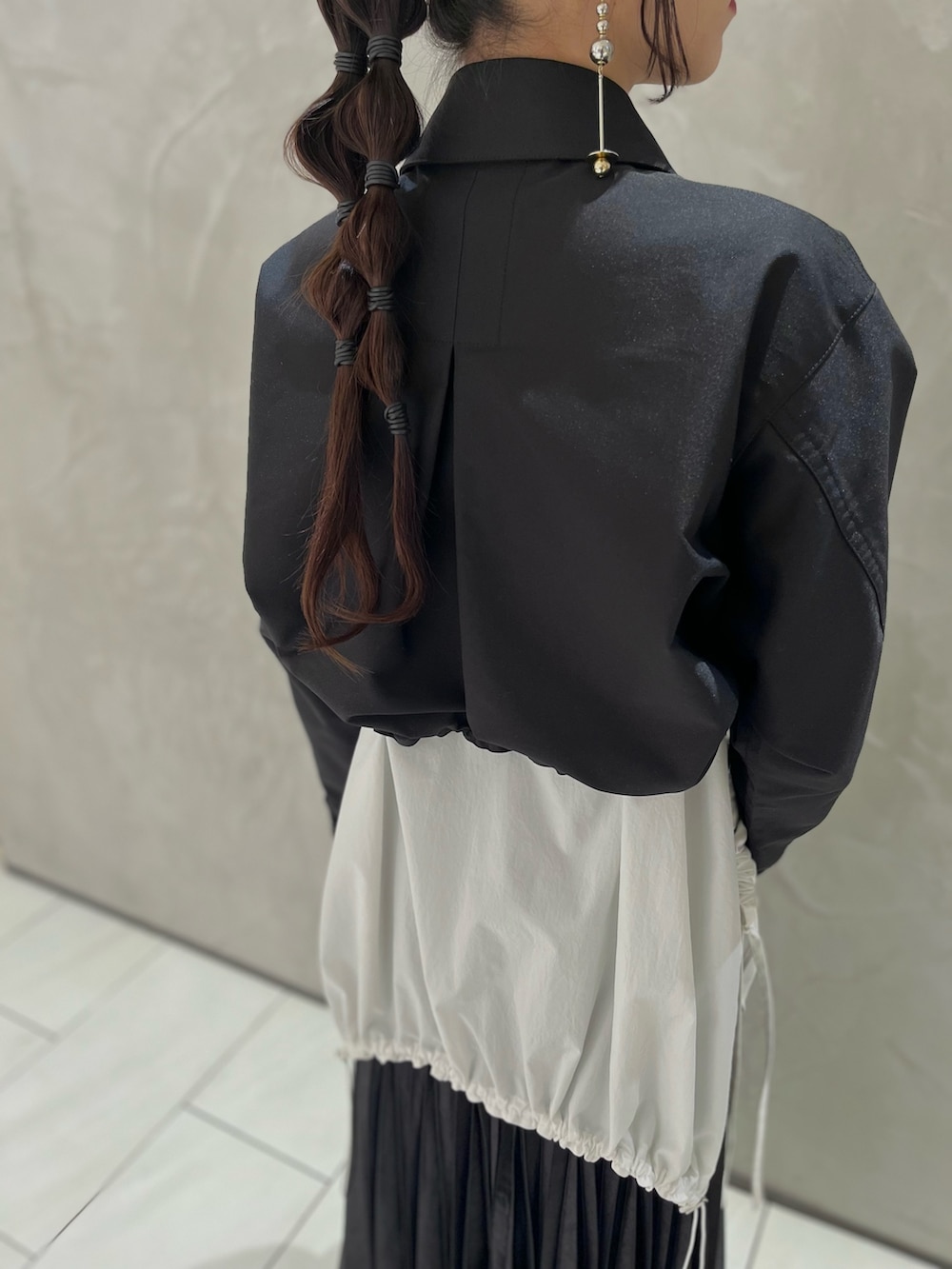 ブラック系のスカート、ホワイト系のシャツ/ブラウス、ブラック系のブルゾンを着用したレディースの秋コーディネートの5枚目の写真