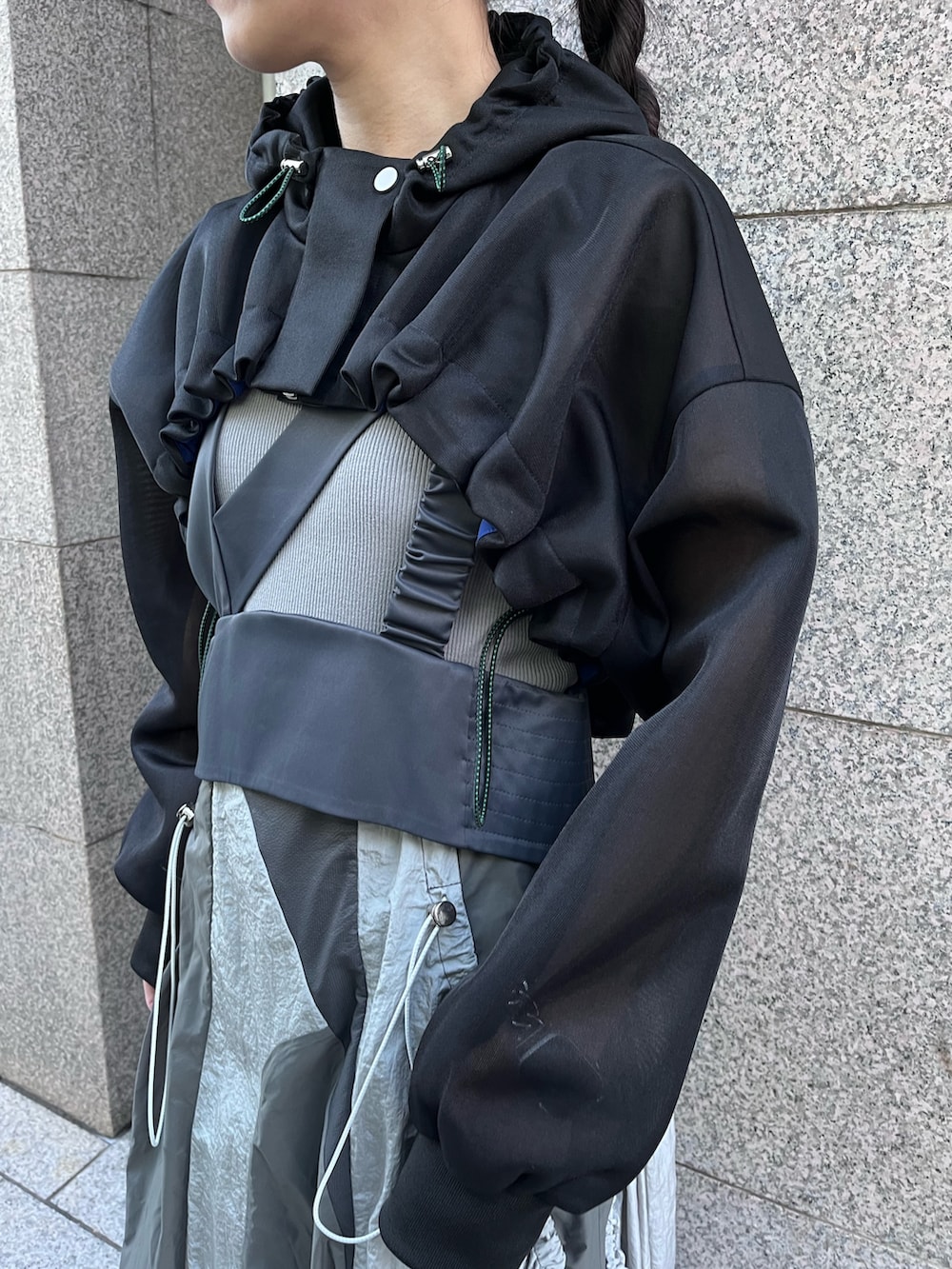 ブラック系のブルゾン、グレー系のタンクトップ、グレー系のジャンパースカートを着用したレディースの春コーディネートの4枚目の写真