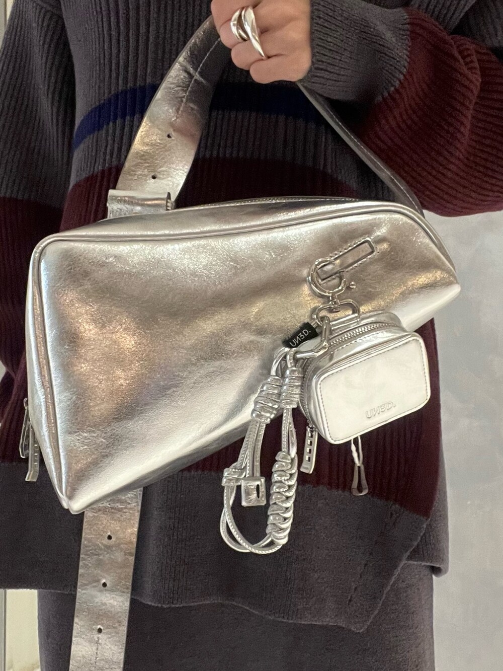 シルバー系のスニーカー、シルバー系のショルダーバッグ、グレー系のニット/セーターを着用したレディースの冬コーディネートの7枚目の写真