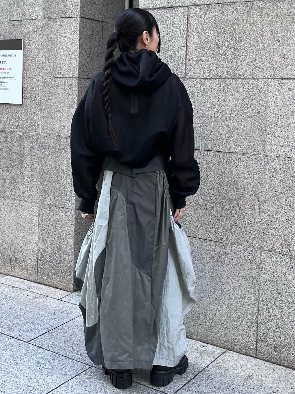 ブラック系のブルゾン、グレー系のタンクトップ、グレー系のジャンパースカートを着用したレディースの春コーディネートの2枚目の写真