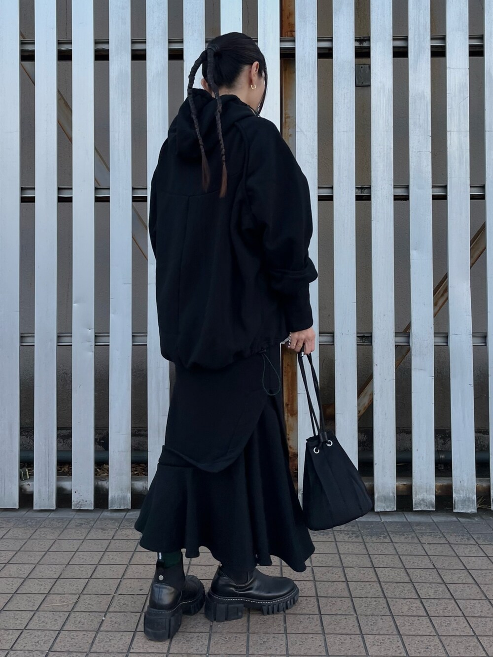 ブラック系のパーカー、ブラック系のスカート、ブラック系のブーツを着用したレディースの冬コーディネートの3枚目の写真