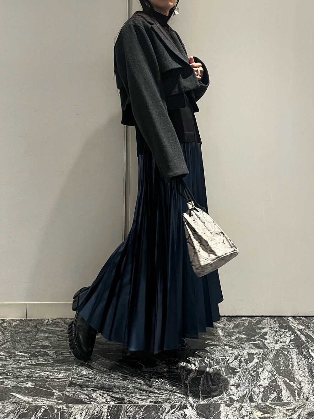 ブルー系のスカート、ブラック系のブーツ、その他のショルダーバッグを着用したレディースの秋コーディネートの2枚目の写真