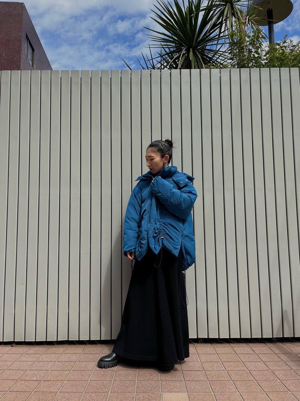 ブルー系のダウンジャケット/コート、ブラック系のワンピース、ブラック系のブーツを着用したレディースの秋コーディネートの3枚目の写真