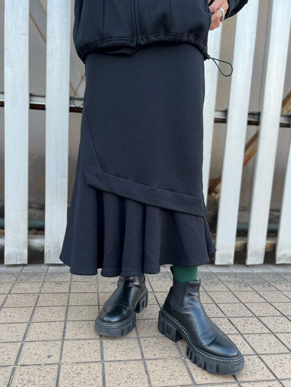 ブラック系のパーカー、ブラック系のスカート、ブラック系のブーツを着用したレディースの冬コーディネートの6枚目の写真