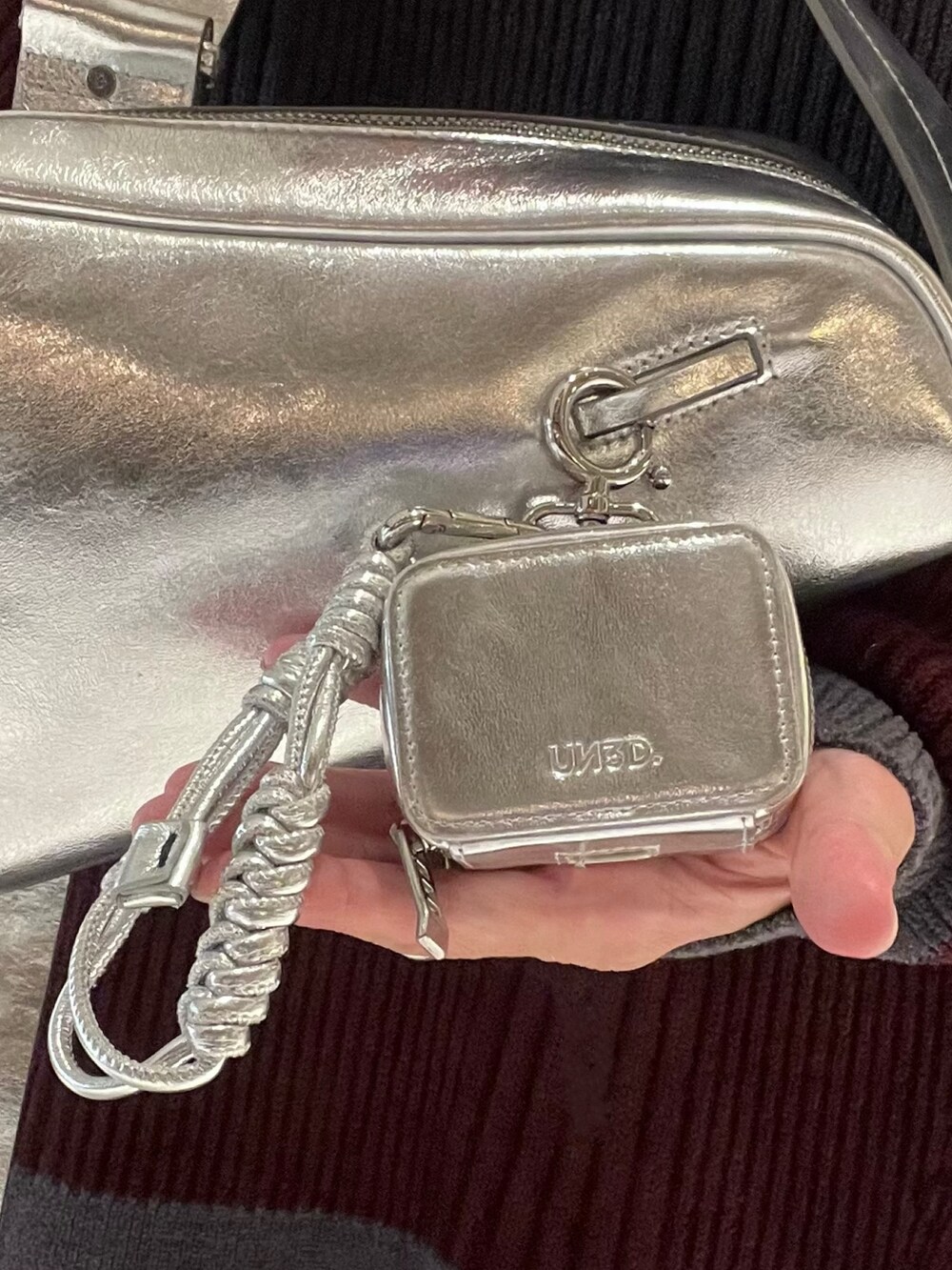 シルバー系のスニーカー、シルバー系のショルダーバッグ、グレー系のニット/セーターを着用したレディースの冬コーディネートの8枚目の写真