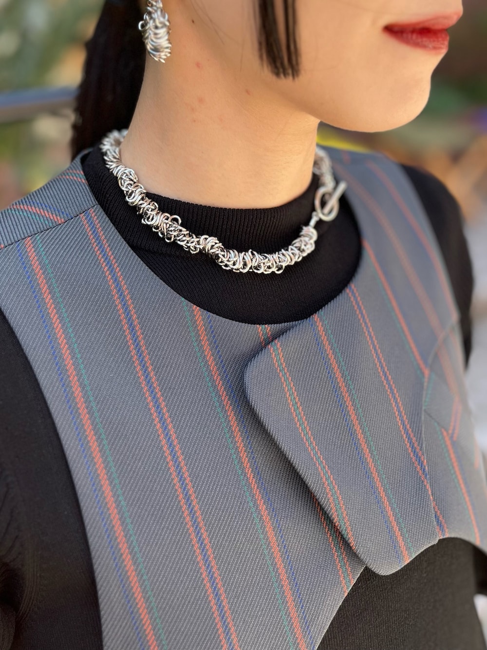 グレー系のスラックス、ブラック系のパンプス、ブラック系のニット/セーターを着用したレディースの春コーディネートの6枚目の写真