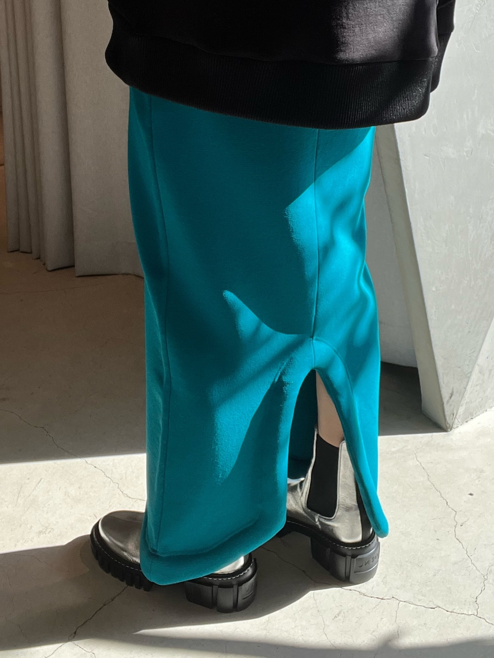 ブラック系のスウェット、ブルー系のスカート、ブラック系のブーツを着用したレディースの冬コーディネートの7枚目の写真