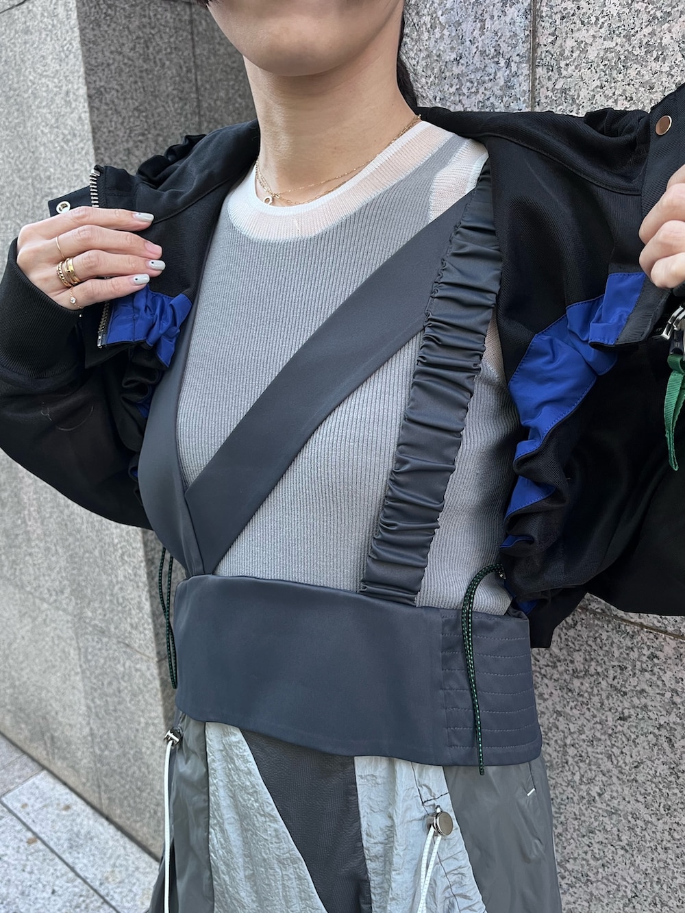 ブラック系のブルゾン、グレー系のタンクトップ、グレー系のジャンパースカートを着用したレディースの春コーディネートの6枚目の写真