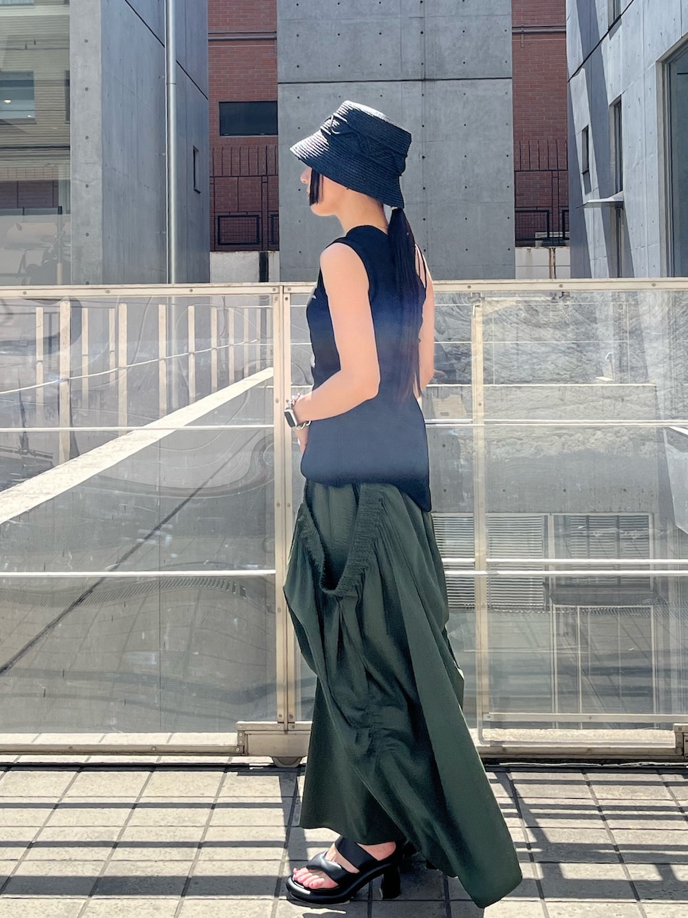 ブラック系のTシャツ/カットソー、グリーン系のスカート、ブラック系のサンダルを着用したレディースの春コーディネートの3枚目の写真