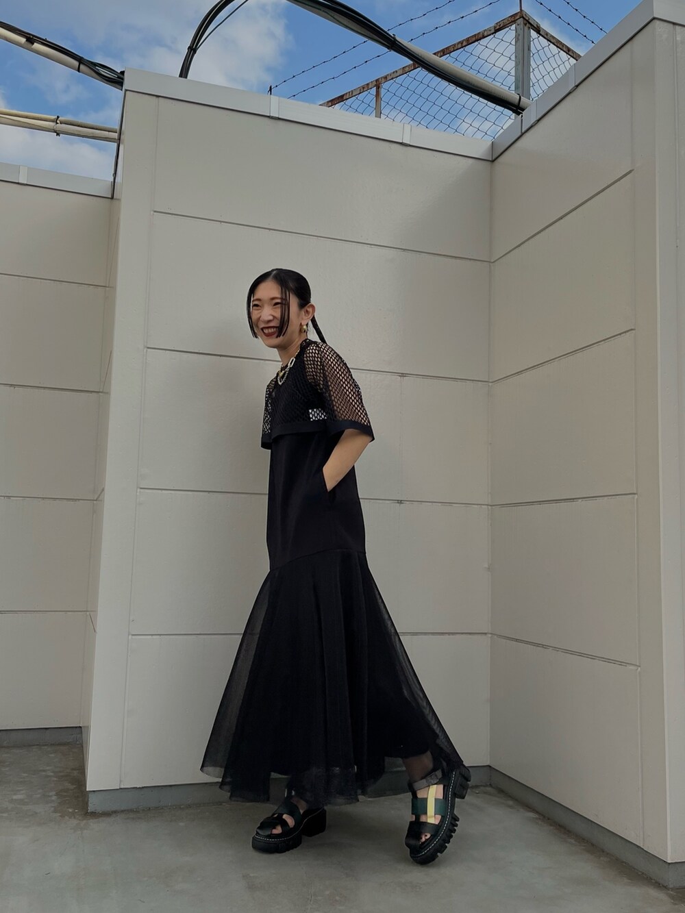 ブラック系のワンピース、その他のサンダル、ゴールド系のネックレスを着用したレディースの春コーディネートの2枚目の写真