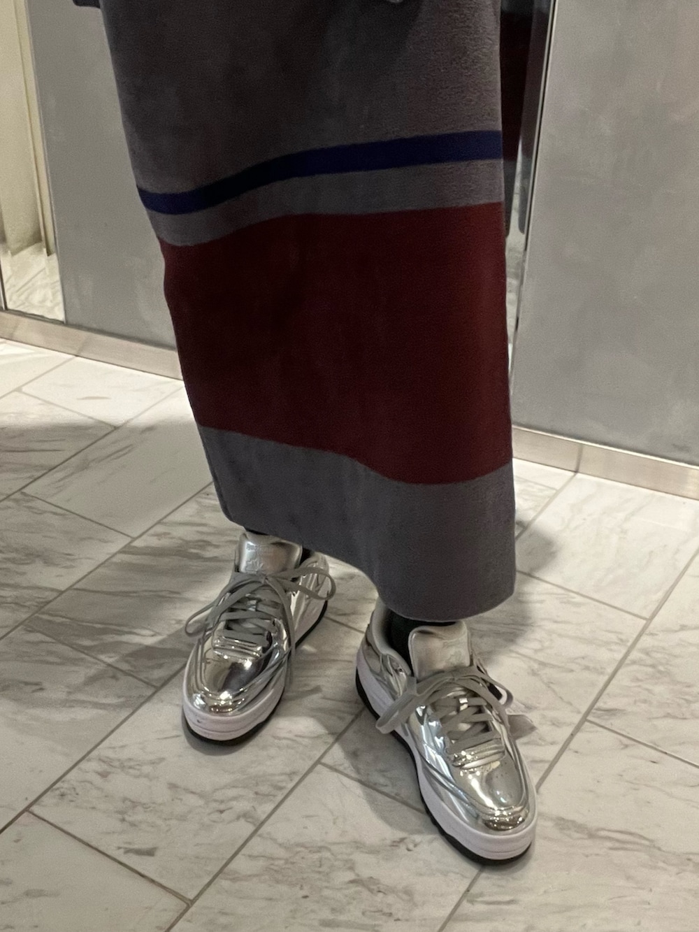 シルバー系のスニーカー、シルバー系のショルダーバッグ、グレー系のニット/セーターを着用したレディースの冬コーディネートの5枚目の写真