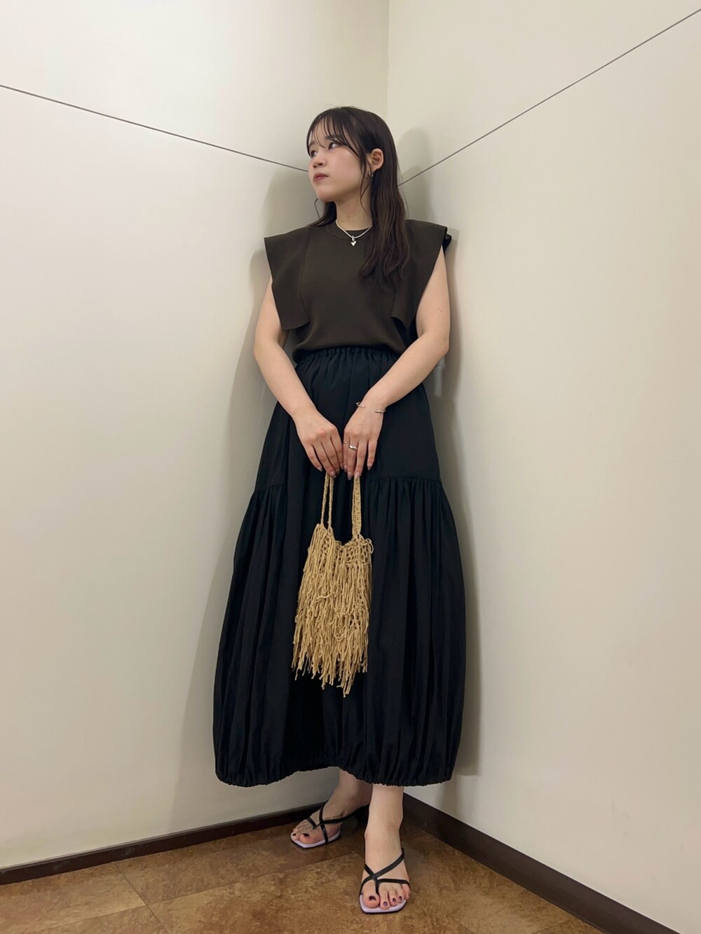 ブラック系のスカート、ブラウン系のニット/セーター、ベージュ系のハンドバッグを着用したレディースの夏コーディネートの4枚目の写真