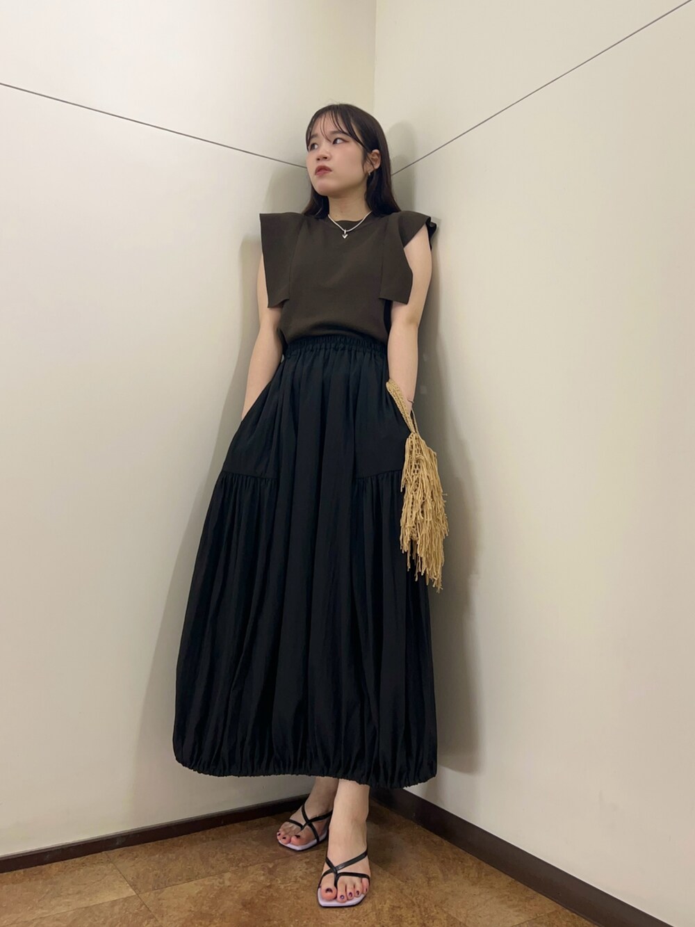 ブラック系のスカート、ブラウン系のニット/セーター、ベージュ系のハンドバッグを着用したレディースの夏コーディネートの5枚目の写真