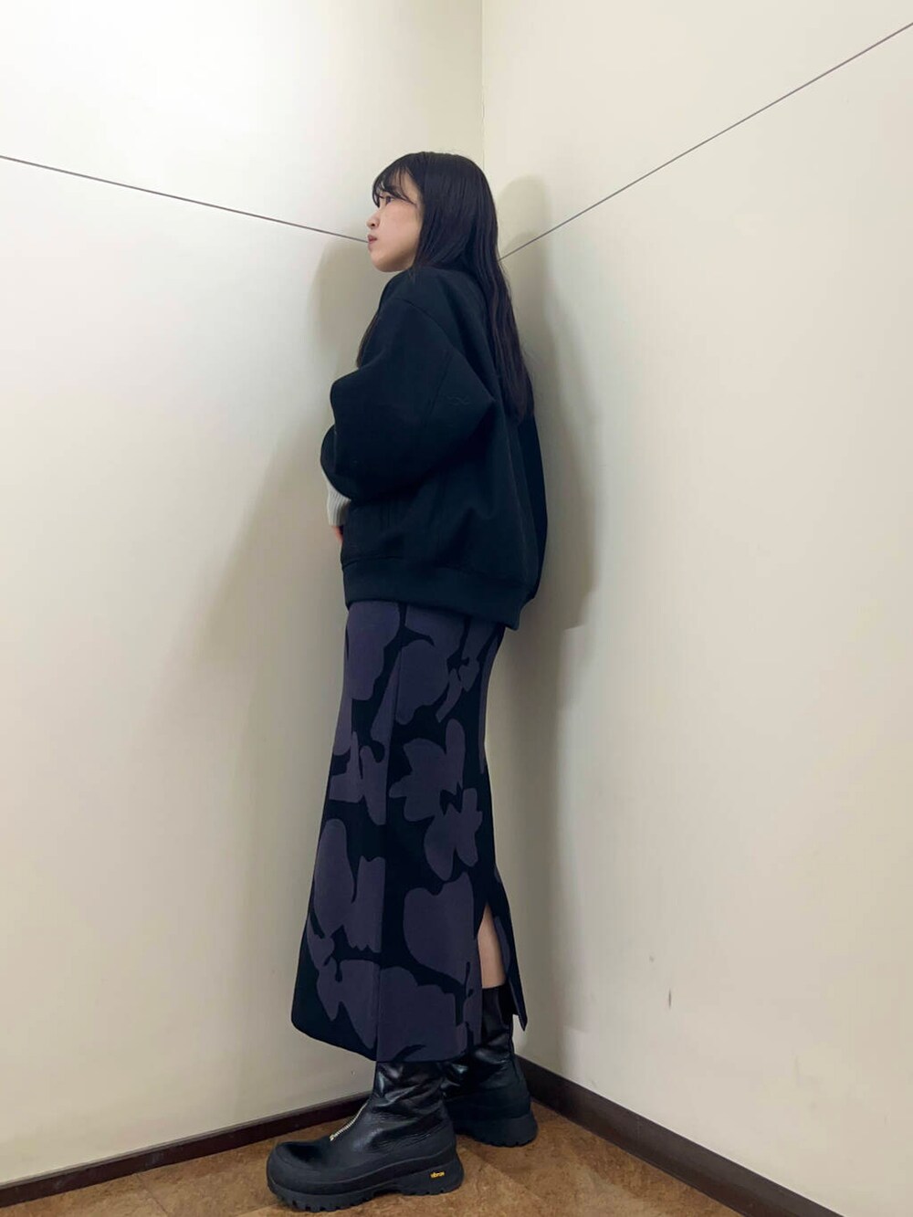 グレー系のニット/セーター、ブラック系のスタジャン、ブラック系のスカートを着用したレディースの秋コーディネートの2枚目の写真