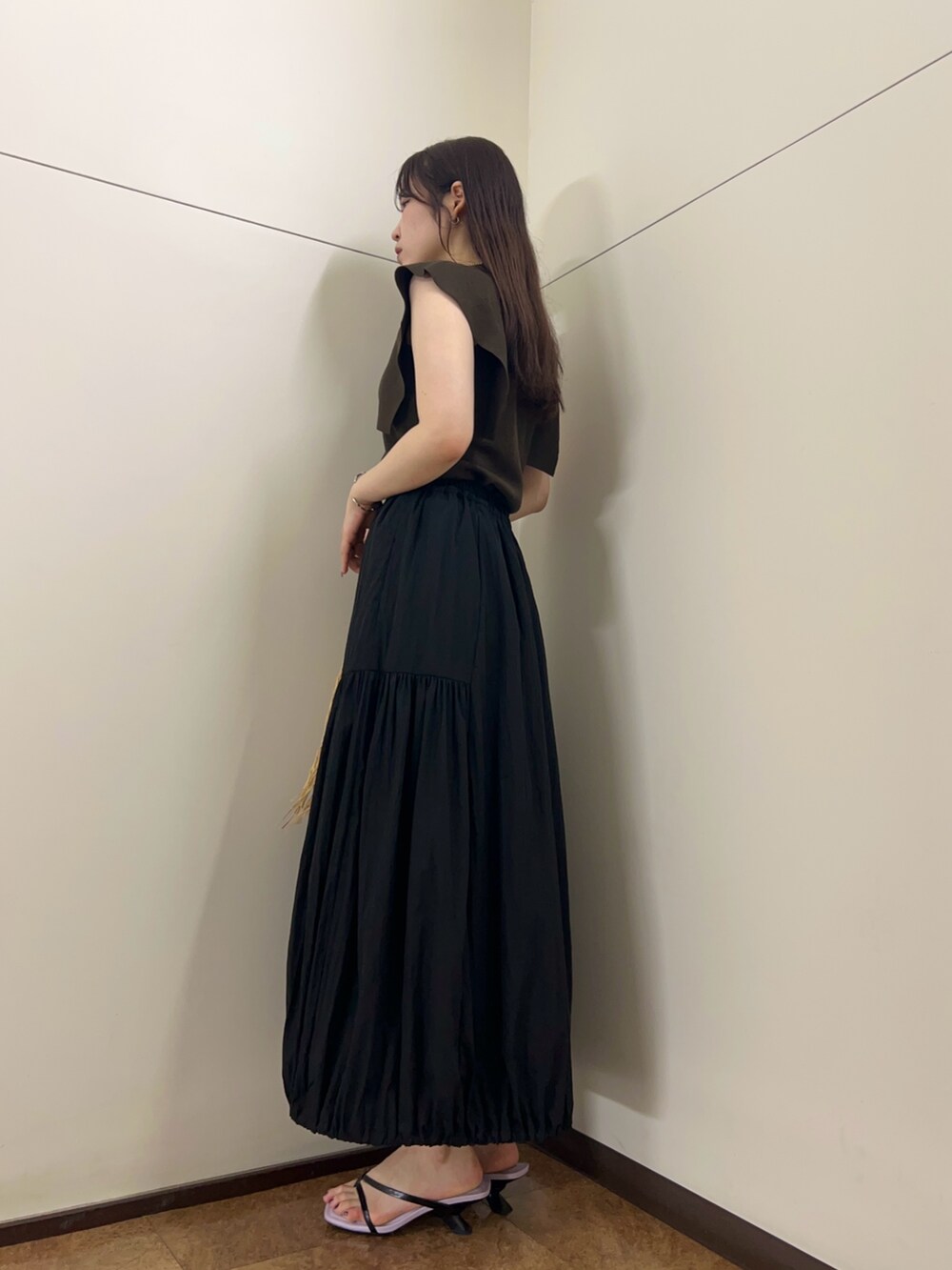 ブラック系のスカート、ブラウン系のニット/セーター、ベージュ系のハンドバッグを着用したレディースの夏コーディネートの2枚目の写真