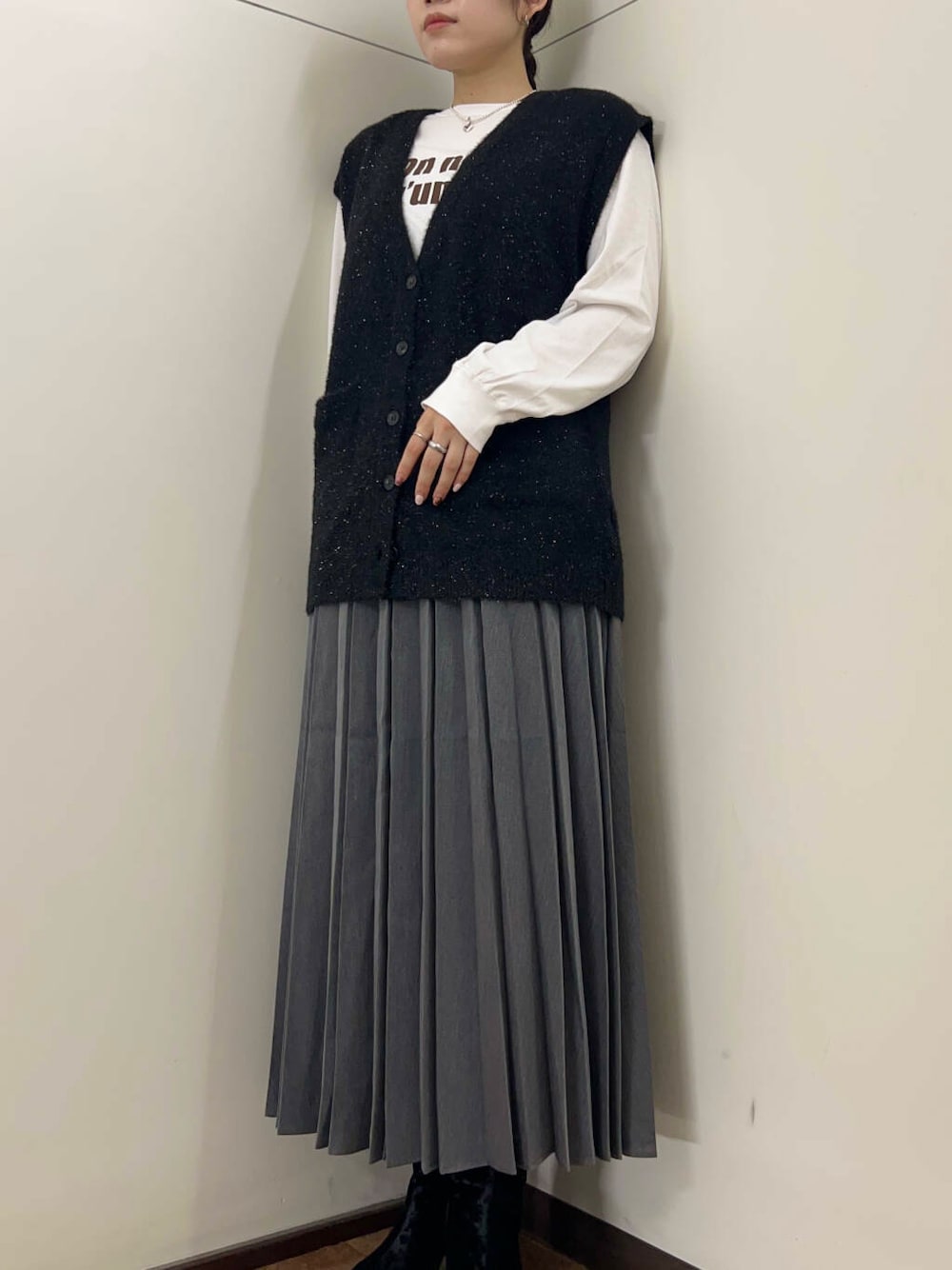 グレー系のスカート、ホワイト系のTシャツ/カットソー、ブラック系のベストを着用したレディースの秋コーディネートの3枚目の写真