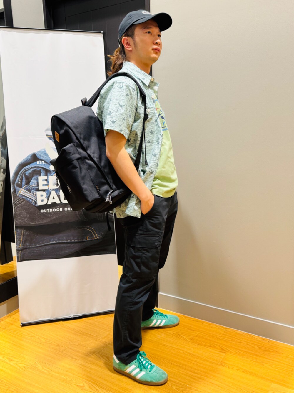 グリーン系のTシャツ/カットソー、グリーン系のシャツ/ブラウス、ブラック系のバックパック/リュックを着用したメンズの春コーディネートの2枚目の写真