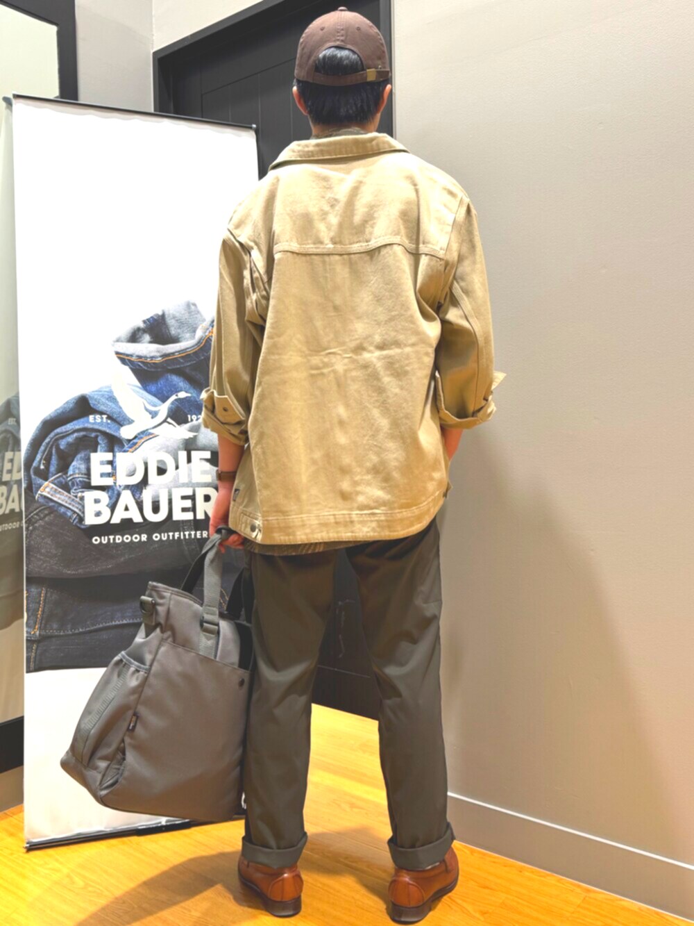 グレー系のバックパック/リュック、ベージュ系のブルゾン、グリーン系のチノパンツを着用したメンズの春コーディネートの2枚目の写真