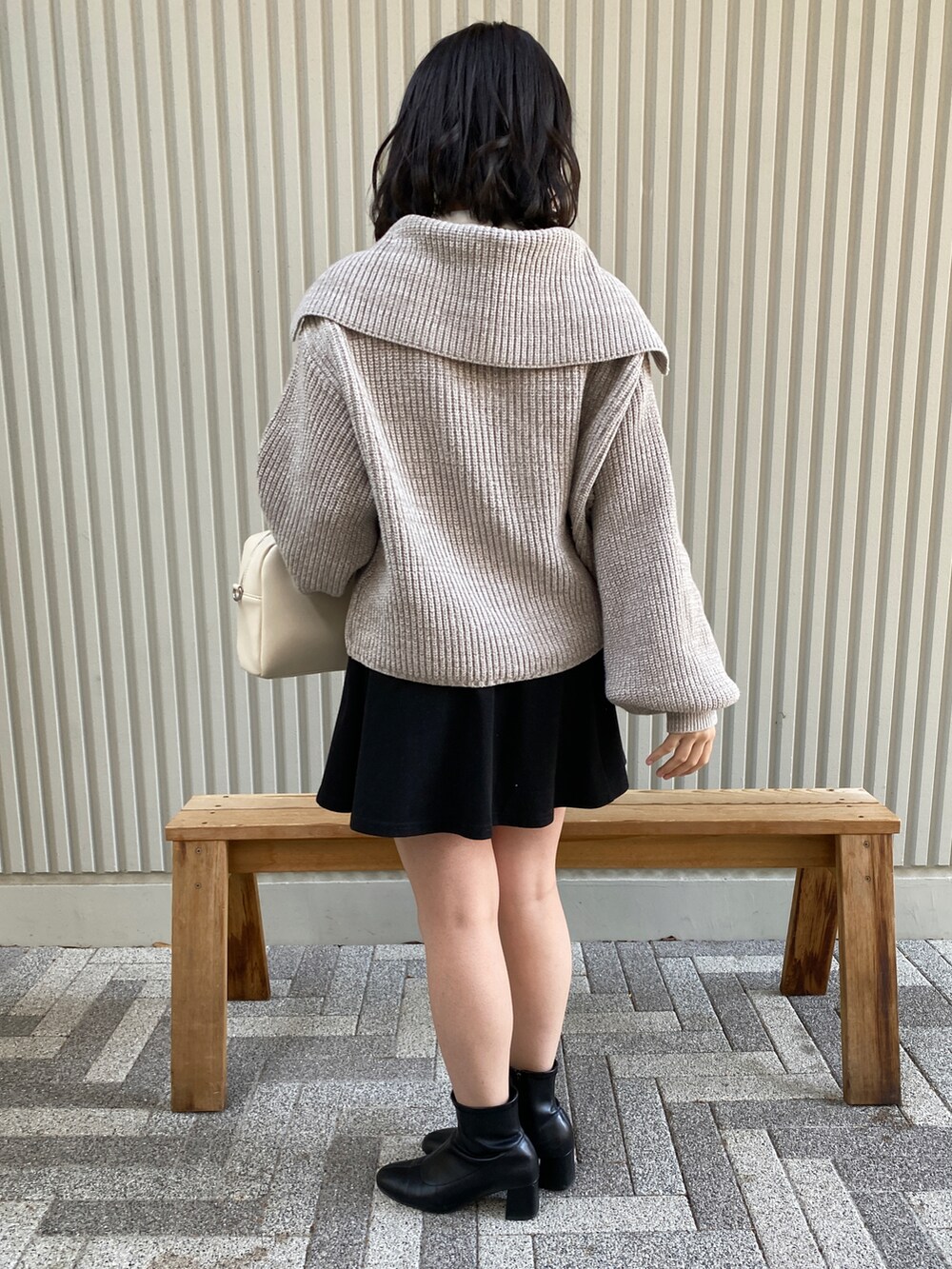 ホワイト系のショルダーバッグ、グレー系のカーディガン/ボレロ、ブラック系のブーツを着用したレディースの冬コーディネートの2枚目の写真